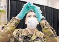  ?? K.M. Cannon Las Vegas Review-journal @Kmcannonph­oto ?? Nevada National Guard Spc. Katherine Deskins prepares to administer a Pfizer vaccine shot Feb. 4 at the Cashman Center COVID-19 vaccinatio­n site in Las Vegas.