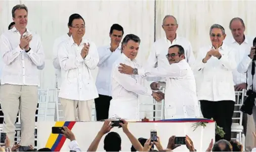  ??  ?? MEETING POINT: President Juan Manuel Santos, front left, and Commander Rodrigo Londono shake hands after signing the peace deal