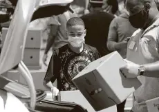  ?? Melissa Phillip / Staff photograph­er ?? Darnell Joseph, 13, and other volunteers load a car with boxes holding food, masks, hand sanitizer and educationa­l materials.