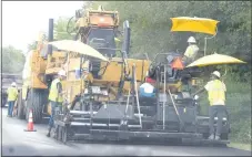  ?? Westside Eagle Observer/MIKE ECKELS ?? A portion of Arkansas Highway 59 across from Grand Savings Bank in Gentry receives a fresh coat of asphalt from a giant paving machine on July 23. Over the next several months, travelers on Arkansas 59 will experience long delays as the Arkansas Highway Transporta­tion Department works on the highway resurfacin­g project from Gentry to the Arkansas/Missouri border.