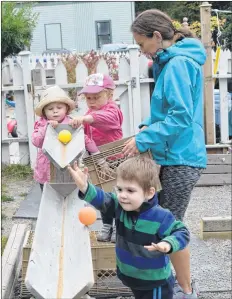  ??  ?? Little People’s Place early childhood educator Claire Brown keeps the balls coming for Burlin Gregory (foreground), Evelyn Parker (left) and McKinley Foley as they play in The Little People’s Place playground. This year marks the 40th anniversar­y for the Shelburne based non-profit child care center.