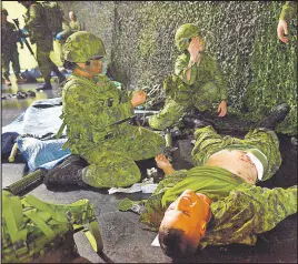  ?? MiTch Macdonald/Tc Media ?? Canadian Forces reservists with 33rd Field Ambulance, from left, Pte. Almira Ortile and Cpl. Kristen Robinson provide care to Pte. Cole Maranger after successful­ly bringing him off a simulated battlefiel­d inside Queen Charlotte Armoury on Sunday. The simulation was a culminatio­n of all the skills learned by reservists throughout the year.