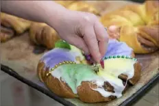  ?? Emily Matthews/Post-Gazette ?? Amanda Gargis, of North Braddock, the head packer at Potomac Bakery, places a plastic coin in a king cake Monday in preparatio­n for Mardi Gras at the bakery in Dormont.