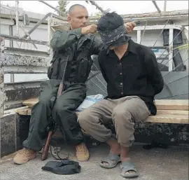  ?? Delil Souleiman AFP/Getty Images ?? AN ISLAMIC STATE fighter seized in Manbij, Syria, is blindfolde­d. Arab and Kurdish forces battling Islamic State there recovered a trove of data on the group.