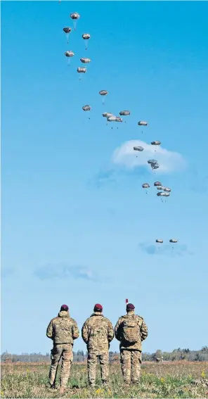  ?? ?? Parachute Regiment Battlegrou­p members watch their colleagues descend onto a field in Central Estonia
