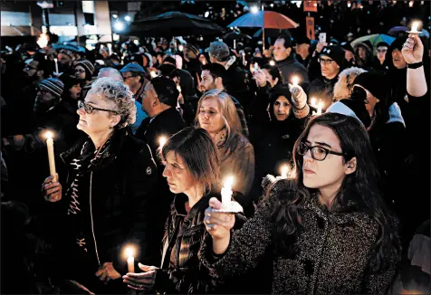  ?? MATT ROURKE/AP ?? People hold candles as they gather for a vigil in the aftermath of a deadly shooting at the Tree of Life Congregati­on.