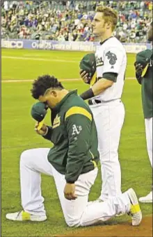  ??  ?? Oakland’s Bruce Maxwell becomes first MLB player to take a knee during anthem, and teammate Mark Canha (r.) places hand on A’s catcher’s shoulder in show of support.