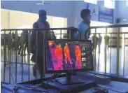  ?? K.M. Chaudary / Associated Press ?? Passengers pass a thermal scanner to check for virus symptoms at a rail station in Lahore, Pakistan.