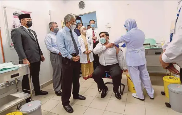  ?? BERNAMA PIC ?? Yang di-Pertuan Agong Al-Sultan Abdullah Ri’ayatuddin Al-Mustafa Billah Shah looks on as a Covid-19 vaccine shot is administer­ed to a frontliner at the Kuala Lumpur Health Clinic vaccinatio­n centre yesterday.