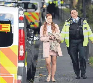  ??  ?? A police officer escorts an injured woman from the scene at Parsons Green Undergroun­d Station.