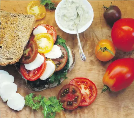  ??  ?? The ripe tomatoes in this tasty sandwich are accompanie­d with pesto mayo, spicy greens and bocconcini cheese.