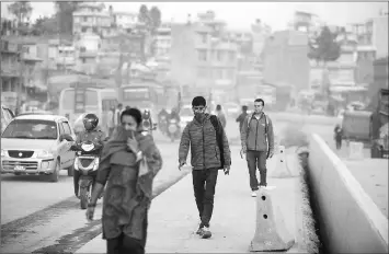  ??  ?? Pedestrian­s cover their faces as they walk along a dusty road in Kathmandu.