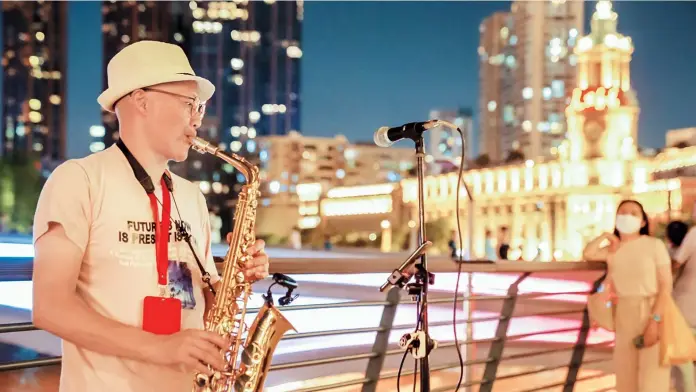  ??  ?? On a waterfront plaza between Garden Bridge and Zhapu Road Bridge, a busker plays the saxophone and Irish whistle in turns. — Hu Jun