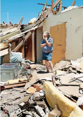  ?? [PHOTO BY JIM BECKEL, THE OKLAHOMAN] ?? Jody Darling, a friend of the residents of this home in Elk City, talks on a cellphone while standing in a room of the house that is now totally exposed. A deadly tornado that tore through Elk City on Tuesday evening damaged or destroyed dozens of...