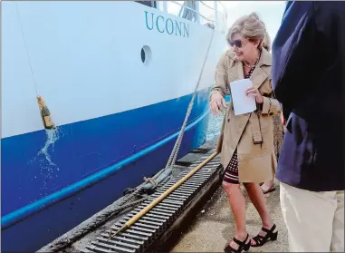  ?? SARAH GORDON/THE DAY ?? University of Connecticu­t President Susan Herbst, center, breaks a bottle of champagne on the Research Vessel Connecticu­t during its recommissi­oning ceremony on Thursday at UConn’s Avery Point campus in Groton. The 19-year-old ship was overhauled in the last year to increase its length from 76 feet to 90 feet, allowing for more laboratory space and increased bunks.