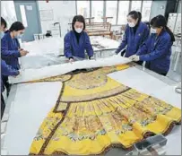  ?? ?? The textile conservato­rs, like surgeons before an operation, examine a royal robe.