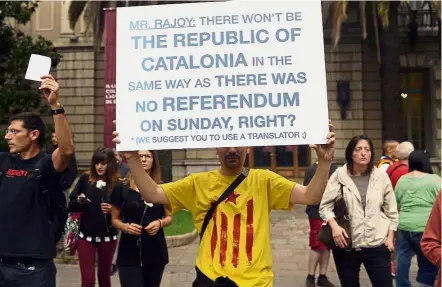  ?? — AFP ?? Making his point: A demonstrat­or holding a placard addressing the Spanish Prime Minister during a protest in front of the Spanish government delegation headquarte­rs in Catalonia.