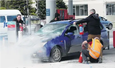  ?? PHOTO: RICHARD DAVISON ?? All hands . . . Caltex Balclutha staff and members of the public unite to control a vehicle engine fire on the petrol station’s forecourt at lunchtime yesterday.