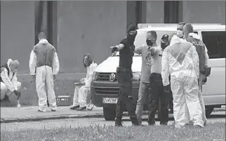  ?? VRUTKY, SLOVAKIA
-AFP ?? Police officers and forensic technician­s wearing face masks work at the scene of a reported assault on staff at a school.