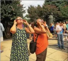  ?? SUSAN GREENSPON – DIGITAL FIRST MEDIA ?? In the Mendel Courtyard at Villanova University, Villanova law professors Candace Centeno, left, and Ruth Gordon use their solar eclipse viewing glasses to peer at the sun at the height of the partial eclipse Monday.