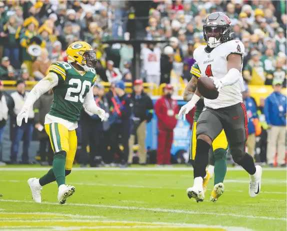  ?? STACY REVERE/GETTY IMAGES ?? Buccaneers running back Rachaad White prances past Rudy Ford of the Green Bay Packers to score a third-quarter TD during Sunday's game at Lambeau Field. The Bucs scored touchdowns on their first three second-half possession­s in a 34-20 victory.