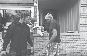  ?? YALONDA M. JAMES/THE COMMERCIAL APPEAL ?? Two young men, who didn’t want to be identified, leave teddy bears at the entrance of Creative Cuts and Design Barber Shop on Jan. 11, a day after a man there was shot dead.