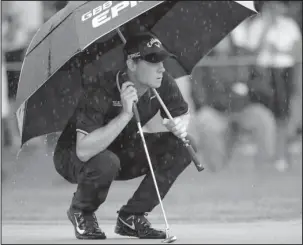  ?? The Associated Press ?? SPLISH, SPLASH: First-round leader Thomas Pieters waits to putt on the first green as rain falls during the second round of the Bridgeston­e Invitation­al Friday at Firestone Country Club in Akron, Ohio. The Belgian shot an even-par 70, putting him two...