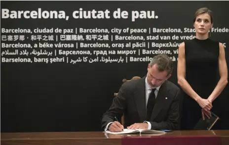  ?? Reuters ?? King Felipe of Spain signs in a book of condolence at the Basilica of the Sagrada Familia in Barcelona yesterday, accompanie­d by his wife, Letizia, before a high mass celebrated in memory of the victims of the terrorist attacks at the weekend