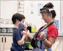  ?? PAUL BERSEBACH — THE ORANGE COUNTY REGISTER ?? A student gets help with his mask from transition­al kindergart­en teacher Annette Cuccarese during the first day of classes at Tustin Ranch Elementary School in Tustin.