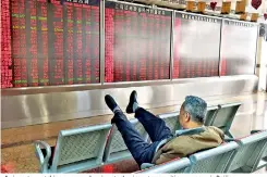  ??  ?? An investor watching a screen showing stock prices at a securities company in Beijing