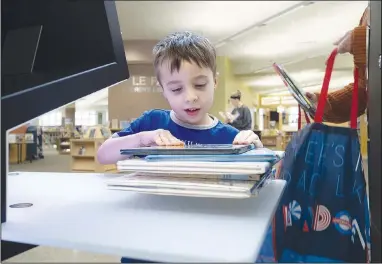  ?? (NWA Democrat-Gazette/Charlie Kaijo) ?? Leo Simmons, 5, of Bentonvill­e checks out books Thursday at the Bentonvill­e Public Library in Bentonvill­e. A contest is underway to design a commemorat­ive library card that will be part of the city’s sesquicent­ennial. Submission­s are due by March 6. The winning design will be unveiled this summer. Visit nwaonline.com/photos for today’s photo gallery.