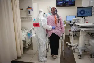  ?? (Yonatan Sindel/Flash90) ?? A SHAARE ZEDEK hospital team member in safety gear helps a pregnant woman in the coronaviru­s ward in February.