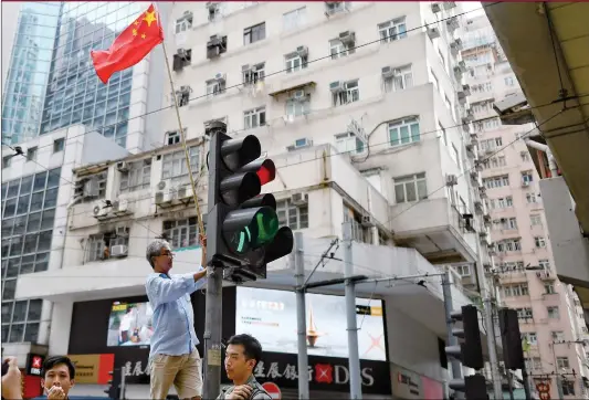  ?? Photo: AFP ?? A Hong Kong resident puts up a Chinese national flag at a traffic intersecti­on in Sham Shui Po area on Sunday.