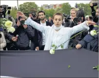  ?? Ap Photo ?? In this April 17, 2012, photo, Syrian actress and activist, Fadwa Suleiman throws roses on a giant Syrian flag during the ‘White Wave’ campaign to protest against the violence in Syria, in Paris. Suleiman died in Paris Thursday.