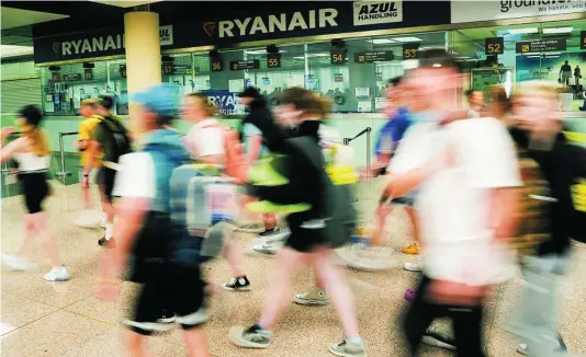  ?? EFE ?? Viajeros pasan por delante de los mostradore­s de Ryanair de el aeropuerto de El Prat
