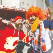  ?? DARREN MAKOWICHUK / POSTMEDIA NEWS ?? Jason Penner, left, and Neil Pandya ham it up as the Flames take on the Edmonton Oilers at the Scotiabank
Saddledome in Calgary on Wednesday.