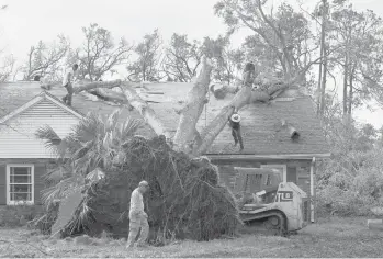  ?? DAVID J. PHILLIP/AP ?? Workers remove a tree that toppled over onto the roof of a home Tuesday in Houma, La., which is 60 miles southwest of New Orleans. Ida slammed into the Louisiana coast as a Category 4 hurricane Sunday.