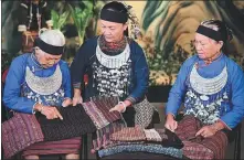  ?? XINHUA ?? Hu Chunfang (center), Li brocade craftswoma­n, who lives in Jiamao town in Hainan province’s Baoting Li and Miao autonomous county, discusses style with other craftswome­n.