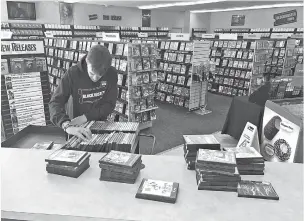  ??  ?? Employee Ryan Larrew alphabetiz­es returned rentals at the last Blockbuste­r store on the planet in Bend, Ore. When a Blockbuste­r in Perth, Australia, shuts its doors for the last time March 31, the Oregon location will be the only one left on the planet.