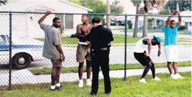  ?? WEST PALM BEACH POLICE DEPARTMENT ?? In this photo taken around 1991 or 1992, West Palm Beach police officer Jeff Nathonson talks to, from left, Willie Louis Parson, an unidentifi­ed man, Gary Alphonso Parson and Stacey Ladrake Parson at Sullivan Park.