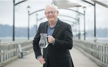  ??  ?? Mayor Wayne Baldwin on the iconic White Rock pier with a jug of the city’s tap water, which will be the subject of an open house on Thursday.