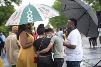  ??  ?? Flanked by supporters, Yasmine Miller and Thomas Gaston cry and hold each other Monday evening as community activists and law enforcemen­t officials discuss the fatal shooting of their 20-month-old son, Sincere Gaston, during the Operation Wake-Up event in Englewood.