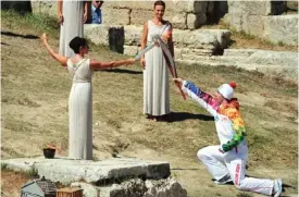  ??  ?? GREECE: Greek actress Ino Menegakie acting as the priestesse­s passes the flame to the first torch bearer, Greek skier Giannis Anoniou, at the Temple . of Hera yesterday during the lighting ceremony in ancient Olympia the sanctuary where H the Olympic...