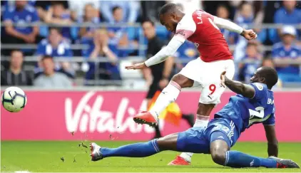  ??  ?? Arsenal’s Alexandre Lacazette, top, scores his side’s third goal during the match against Cardiff City Photo: AP
