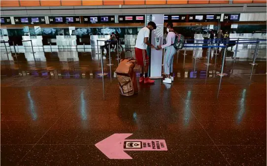  ?? SUZANNE KREITER/GLOBE STAFF ?? At Logan Internatio­nal Airport’s Terminal E, travelers prepared to fly overseas in 2021.