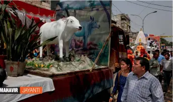  ?? — AP ?? People look at a tableau with the sculpture of a cow during a procession to mark Mahavir Jayanti in New Delhi on Thursday.