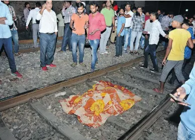  ?? PRABHJOT GILL / THE ASSOCIATED PRESS ?? A cloth covers the body of a victim on a railway track in Amritsar, India, on Friday, after a speeding train plowed through a crowd watching fireworks during a religious festival killing at least 50 people.