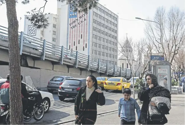  ?? ?? A family walks past an anti-us mural covering the wall of a building in the background in Tehran as tensions between Iran and the US increase