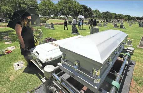  ??  ?? Kristin Urquiza looks at the casket of her father, Mark Anthony Urquiza, after the burial service Wednesday at Holy Cross Cemetery in Avondale. DAVID WALLACE/THE REPUBLIC