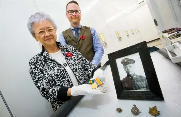  ?? Herald photo by Ian Martens @IMartensHe­rald ?? Pat Sassa, alongside collection­s technician Kevin MacLean, displays First World War service medals and collar badges from her father, Tomomi Okutake, donated to the Galt Museum and Archives.